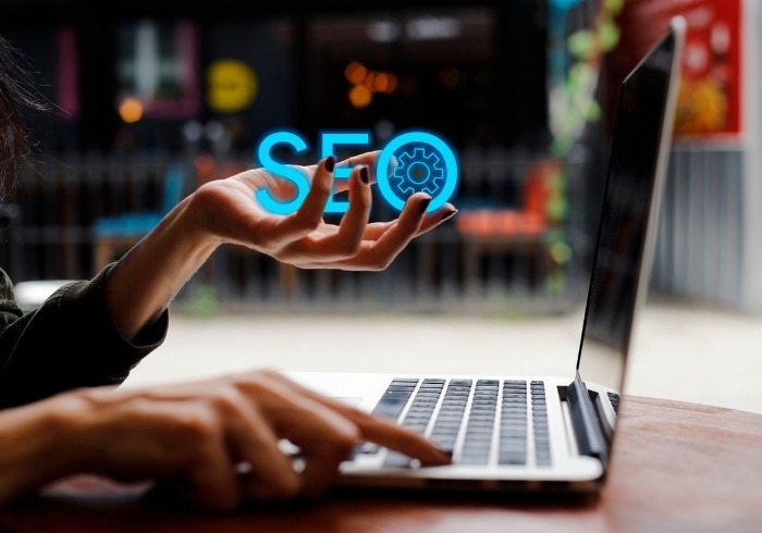 mains à l'ordinateur portable une main tiens les lettres du SEO